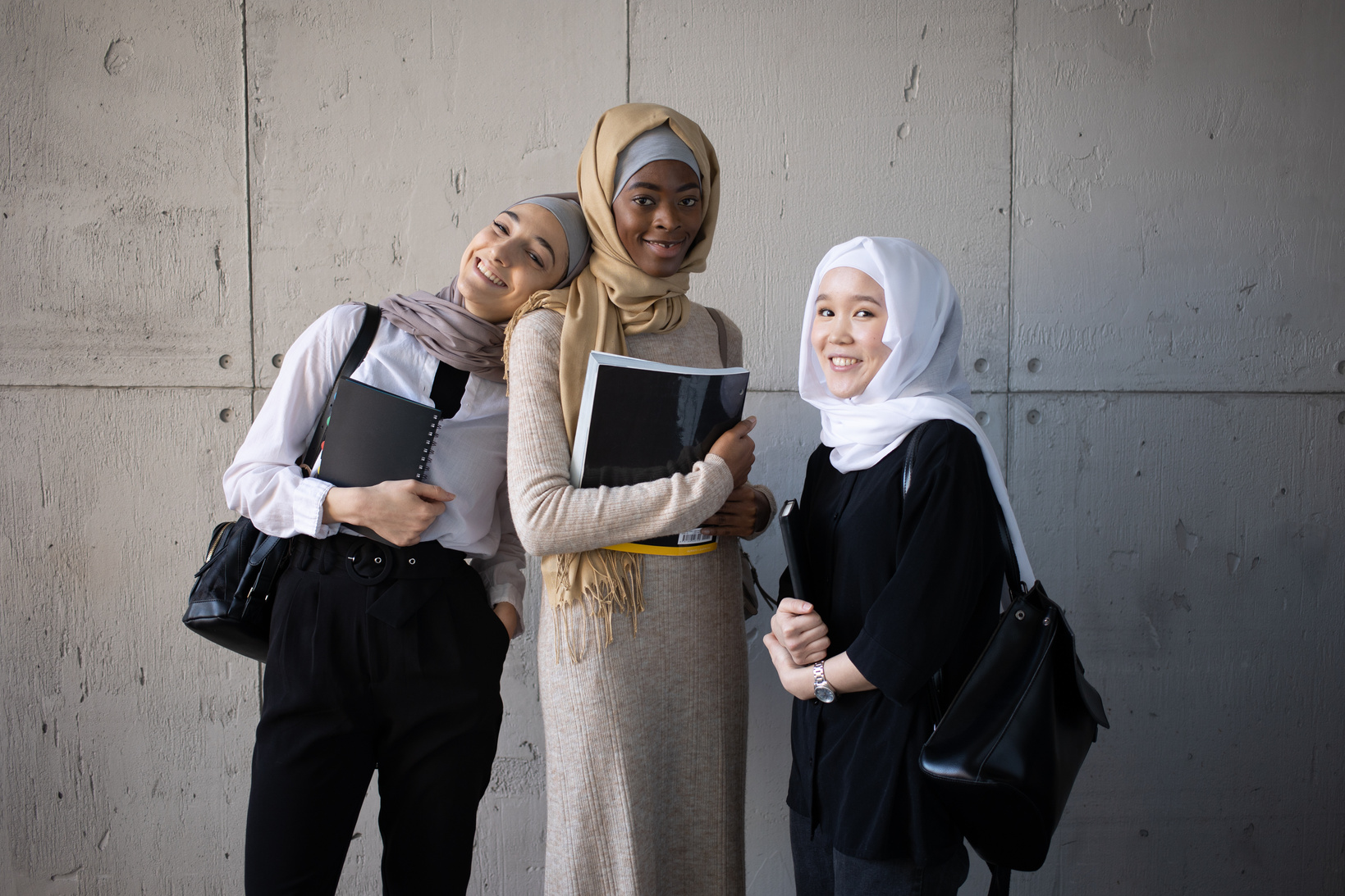 Positive multiracial Muslim women with workbooks in university